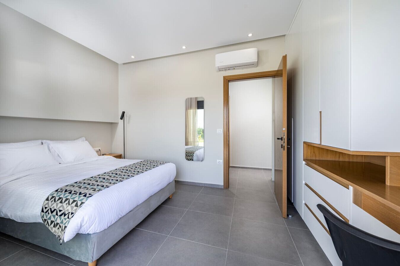 Une chambre moderne avec un grand lit, une télévision et une armoire.