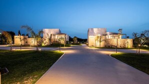 Una zona residencial moderna con dos casas, un camino pavimentado y jardines bien cuidados.