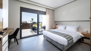 Un dormitorio moderno con una cama grande, un escritorio y una puerta corrediza de vidrio que da a un espacio exterior.