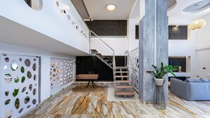 A modern interior with a marble floor, a staircase, and a seating area with a grey sofa. - La Casa Beachside with Jacuzzi (Kos)