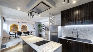 A modern kitchen with a central island, dark wood cabinets, and a stainless steel refrigerator. - La Casa Beachside with Jacuzzi (Kos)