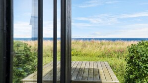 Een houten terras met uitzicht op zee en grasvelden.
