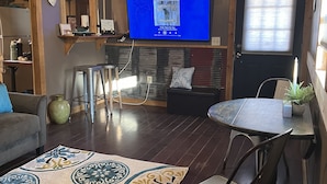 Ein Wohnzimmer mit Fernseher, Esstisch und einem gemusterten Teppich.