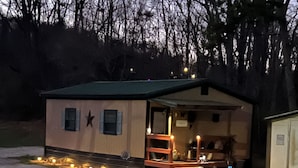 Ein kleines, eingeschossiges Gebäude mit grüner Dachbegrünung und einem sternförmigen Fenster. Es besitzt eine Holzterrasse mit Stufen zum Eingang.