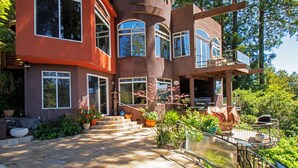 A modern house with a curved facade, large windows, and a stone pathway leading to the entrance. - Palazzo Marzino ~ An Italian Inspired Villa ~ 3 Bed ~ 3 Bath ~ Pool ~ Hot Tub ~ (Guerneville)