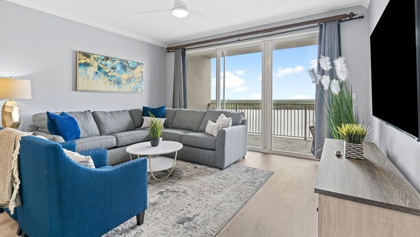 A modern living room with a grey sofa, blue armchair, and a small round table. - Condo is just  2 miles away from Disney, wonderful  Lake view family-sized (Orlando)