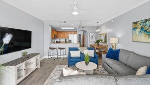 A modern living room with a grey sofa, blue armchairs, a coffee table, and a TV. - Condo is just  2 miles away from Disney, wonderful  Lake view family-sized (Orlando)
