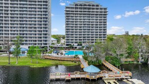 A high-rise hotel with multiple balconies, a swimming pool, and a dock extending into a body of water. - Condo is just  2 miles away from Disney, wonderful  Lake view family-sized (Orlando)