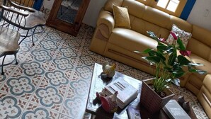 A living room with a beige sofa, a wooden cabinet, and a patterned floor. - Pousada Sinhá Moça Campos Ltda (São João del Rei)