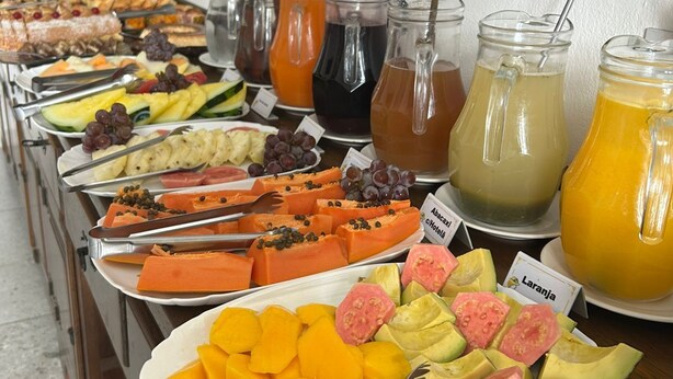 A buffet with various fruits, vegetables, and beverages. - Pousada Sinhá Moça Campos Ltda (São João del Rei)