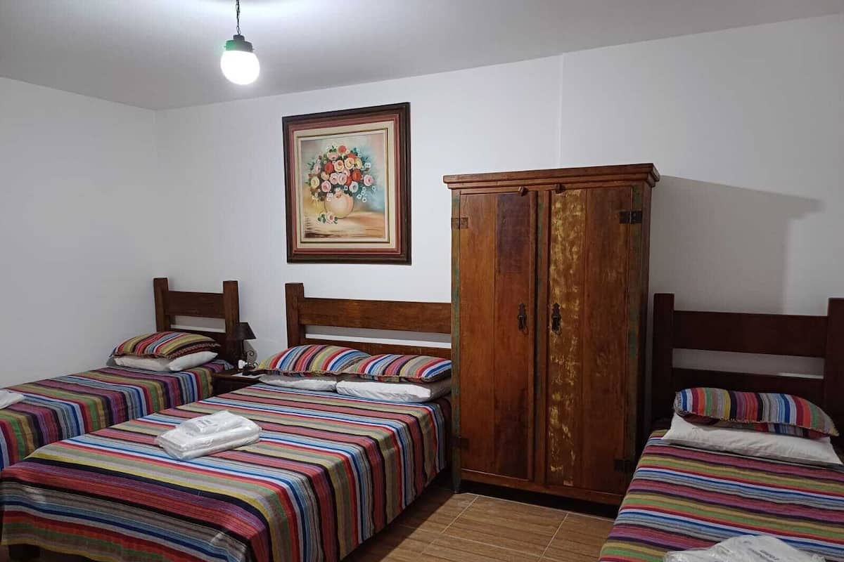 Quarto com duas camas, um guarda-roupa de madeira e um quadro na parede.