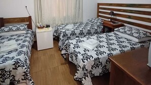 A room with two beds, a small table, a nightstand, a ceiling light, a window with curtains, and a painting on the wall. - Pousada Sinhá Moça Campos Ltda (São João del Rei)