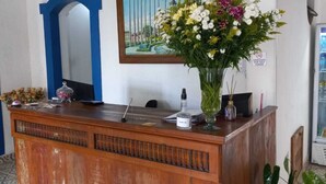 A reception desk with a mirror, a vase of flowers, and a painting on the wall. - Pousada Sinhá Moça Campos Ltda (São João del Rei)