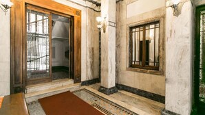 A hallway with marble walls, a wooden door, and a patterned rug. - Apartment Togni "y" (Milano)