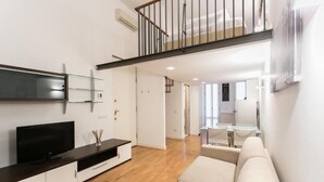 A modern living room with a flat-screen TV, a sofa, and a staircase leading to an upper level. - Apartment Togni "y" (Milano)