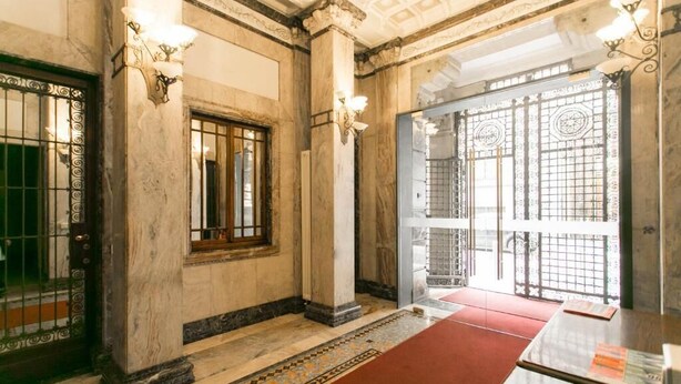 A room with marble walls, a red carpet, and a table with a menu. - Apartment Togni "y" (Milano)