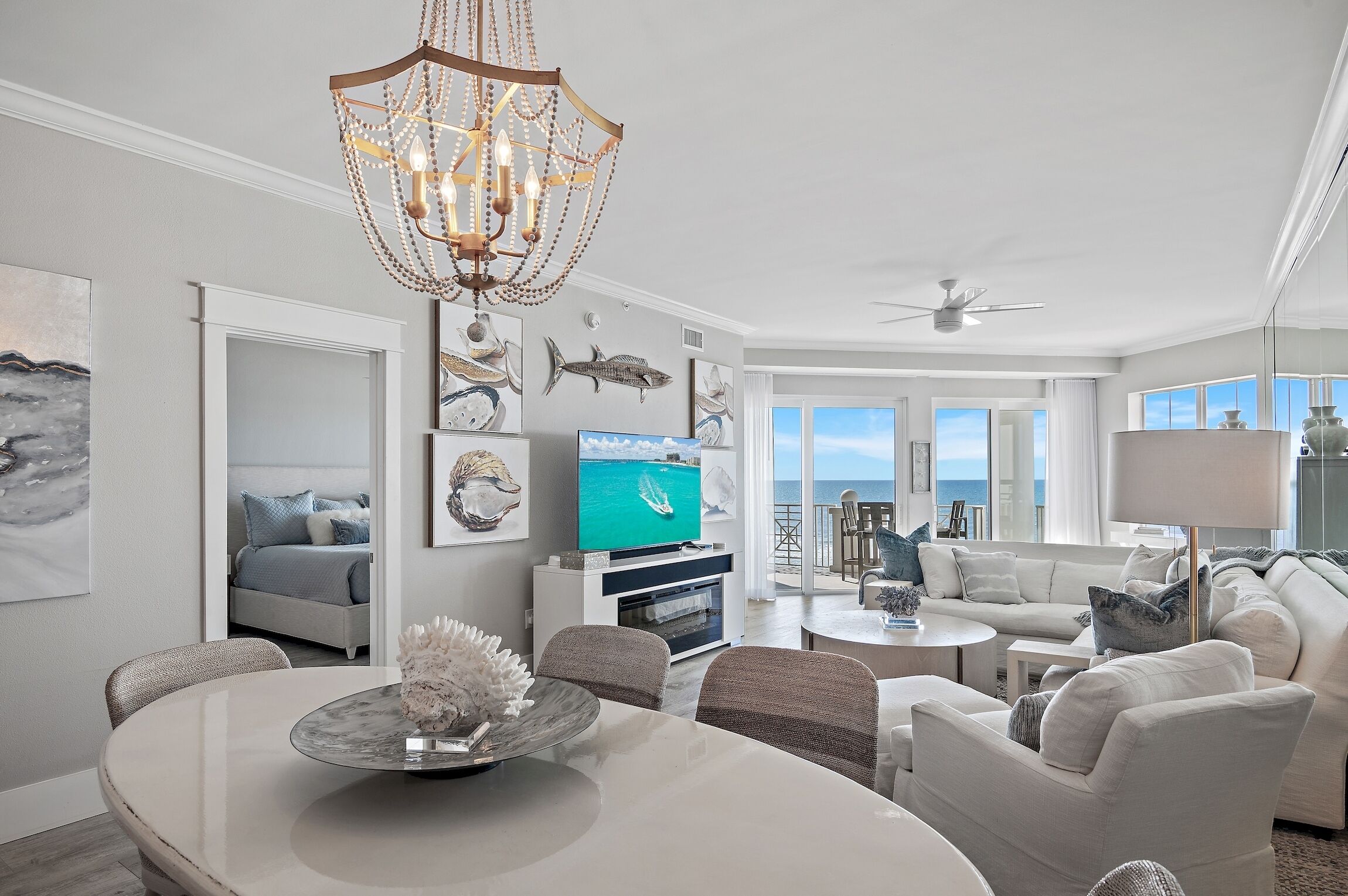 A modern living room with a chandelier, a TV, and a dining area.
