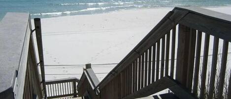 A wooden staircase leading to a beach with a clear view of the ocean.