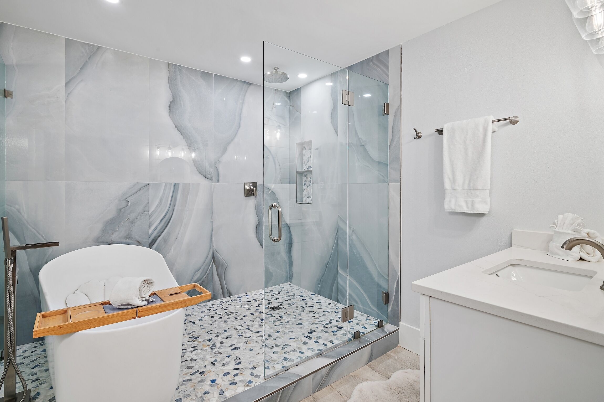 A modern bathroom with a glass-enclosed shower, a white toilet, and a sink with a marble countertop.