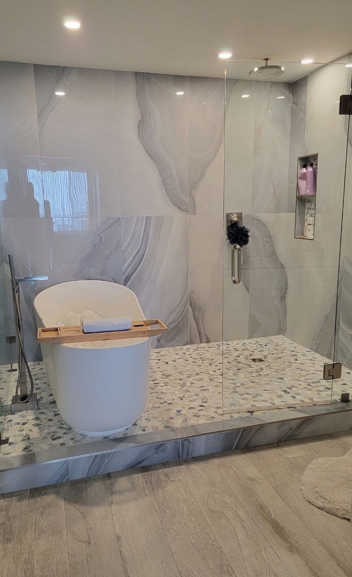 Ein modernes Badezimmer mit Marmorwand, einer weißen Badewanne und einer Duschkabine.