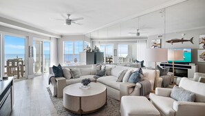 A spacious living room with a large L-shaped sectional sofa, a round coffee table, and a flat-screen TV. - Ahh.. The VIEW! · Gulf Front Beauty · Private Beach & Free Beach Service (Santa Rosa Beach)