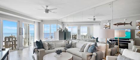 A spacious living room with a large L-shaped sectional sofa, a round coffee table, and a flat-screen TV.