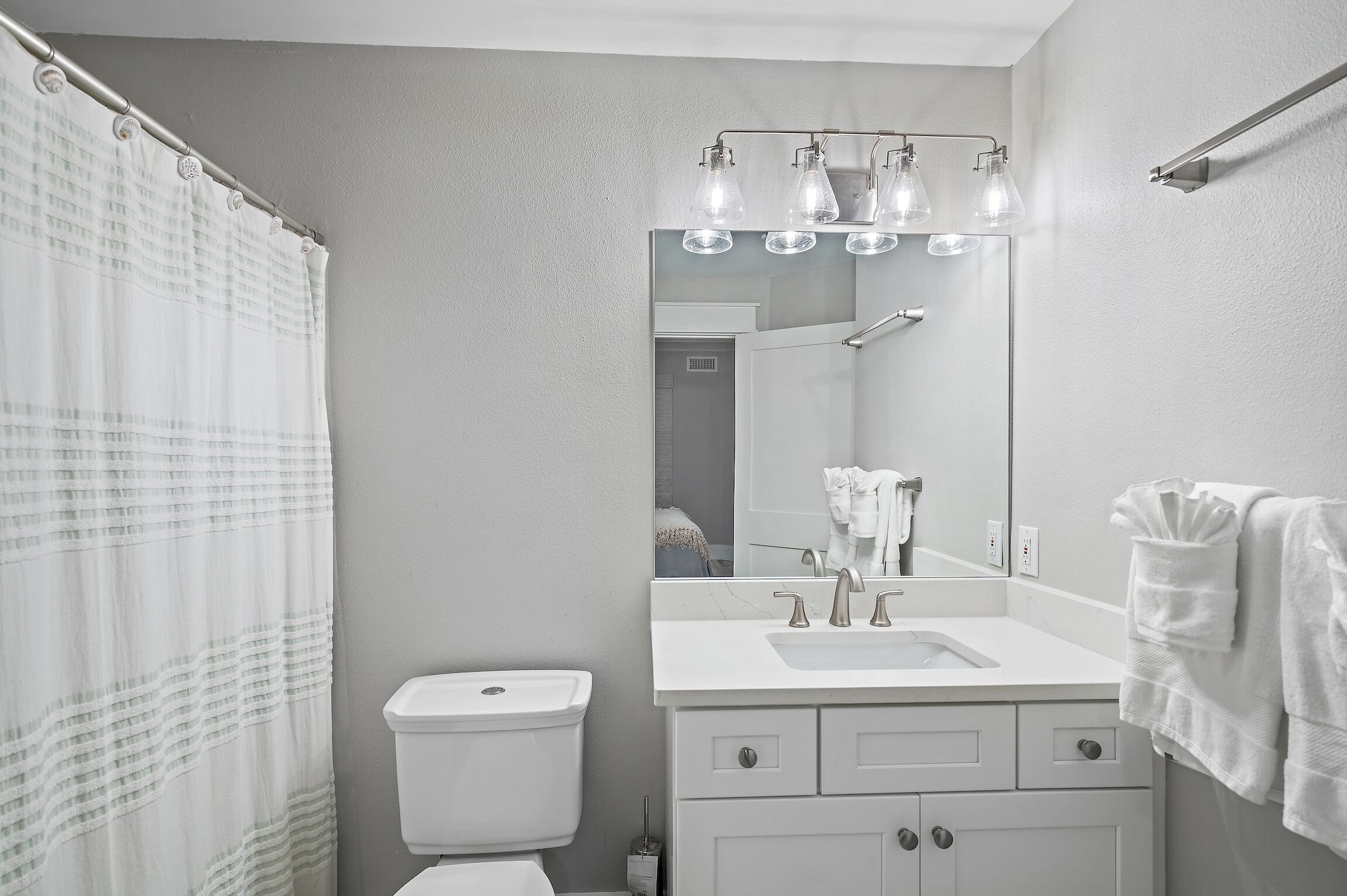 A bathroom with a white sink, mirror, and towel rack.