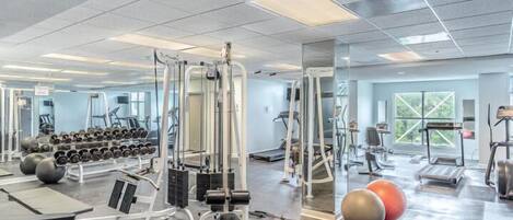 A gym with cardio machines, free weights, and exercise balls.