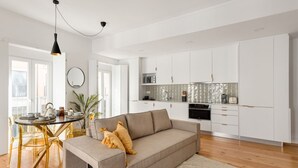 A modern living space with a sofa, dining table, and kitchen area. - JOIVY Central deluxe flat (Lisbon)