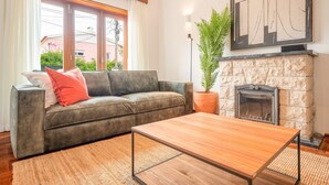 Un salón con sofá, mesa de centro, chimenea y un ventanal grande.