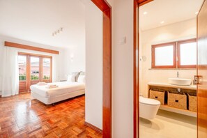 Un dormitorio con piso de madera, una cama y un ventanal grande.
