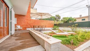 Un patio con un banco de piedra, mobiliario exterior y una pared de madera.