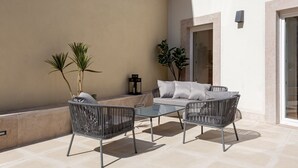 An outdoor patio with a sofa, two chairs, and two potted plants. - JOIVY Splendid downtown penthouse (Lisbon)
