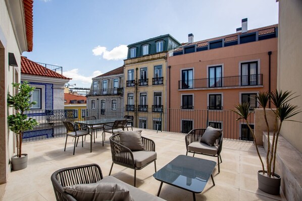 Relax on the rooftop with a glass-top table and wicker chairs, surrounded by lush greenery and city views.