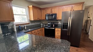 A kitchen with granite countertops, wooden cabinets, a stainless steel refrigerator, and a built-in microwave. - Excellent three bedroom two bath condo close to KU campus  (Lawrence)