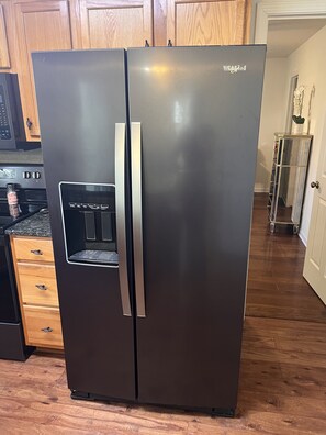 Une cuisine moderne dotée d’un réfrigérateur en acier inoxydable, de meubles en bois et d’un four encastré.