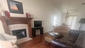 A living room with a fireplace, a television, a sofa, and a ceiling fan. - Excellent three bedroom two bath condo close to KU campus  (Lawrence)