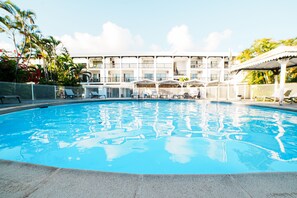 Relax by the pool surrounded by lush greenery and comfortable lounge chairs.