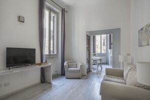 Un salon moderne avec un téléviseur à écran plat, un canapé, un fauteuil et une lampe.