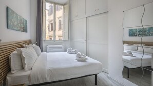 Un dormitori modern amb un llit gran, un armari i una finestra amb vista a edificis.