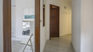 Un passadís amb una porta de fusta, una paret blanca i una finestra amb vistes.