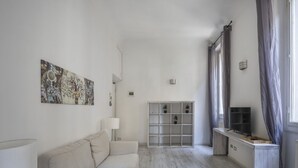 Un saló modern amb un sofà, una televisió, una prestatgeria i una obra decorativa a la paret.