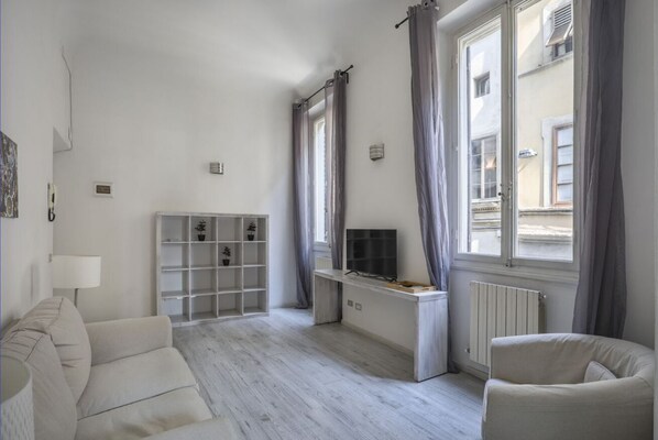 Un salon moderne avec un canapé, un téléviseur et une étagère blanche.