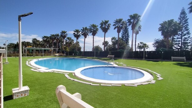 A swimming pool with two distinct sections, surrounded by artificial grass and palm trees. - ACV - Vistamar Iii-1ª Linea Planta 2 Norte 2 (OROPESA)