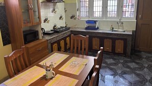 Une cuisine équipée d’une table à manger, de chaises, de placards, d’un four à micro-ondes, d’une cuisinière et d’une fenêtre avec des barreaux.
