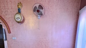 Un salon comprenant un canapé, des coussins à motifs, une table basse, une horloge murale et un éventail décoratif.