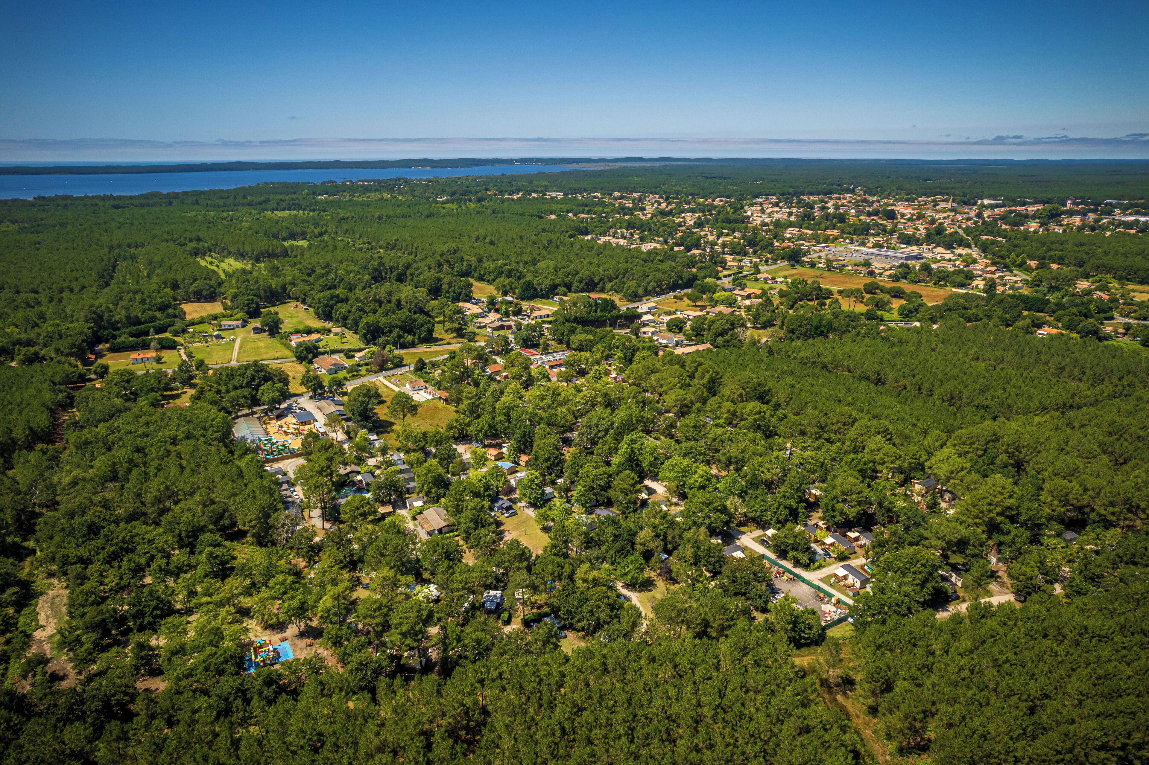 An aerial view of a residential area with houses, roads, and a large body of water in the background.