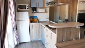 Una kitchenette compacta con microondas, tostadora y un lavamanos pequeño.