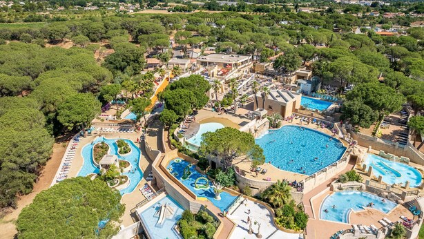 An aerial view of a resort with multiple swimming pools, a water park, and lush greenery.