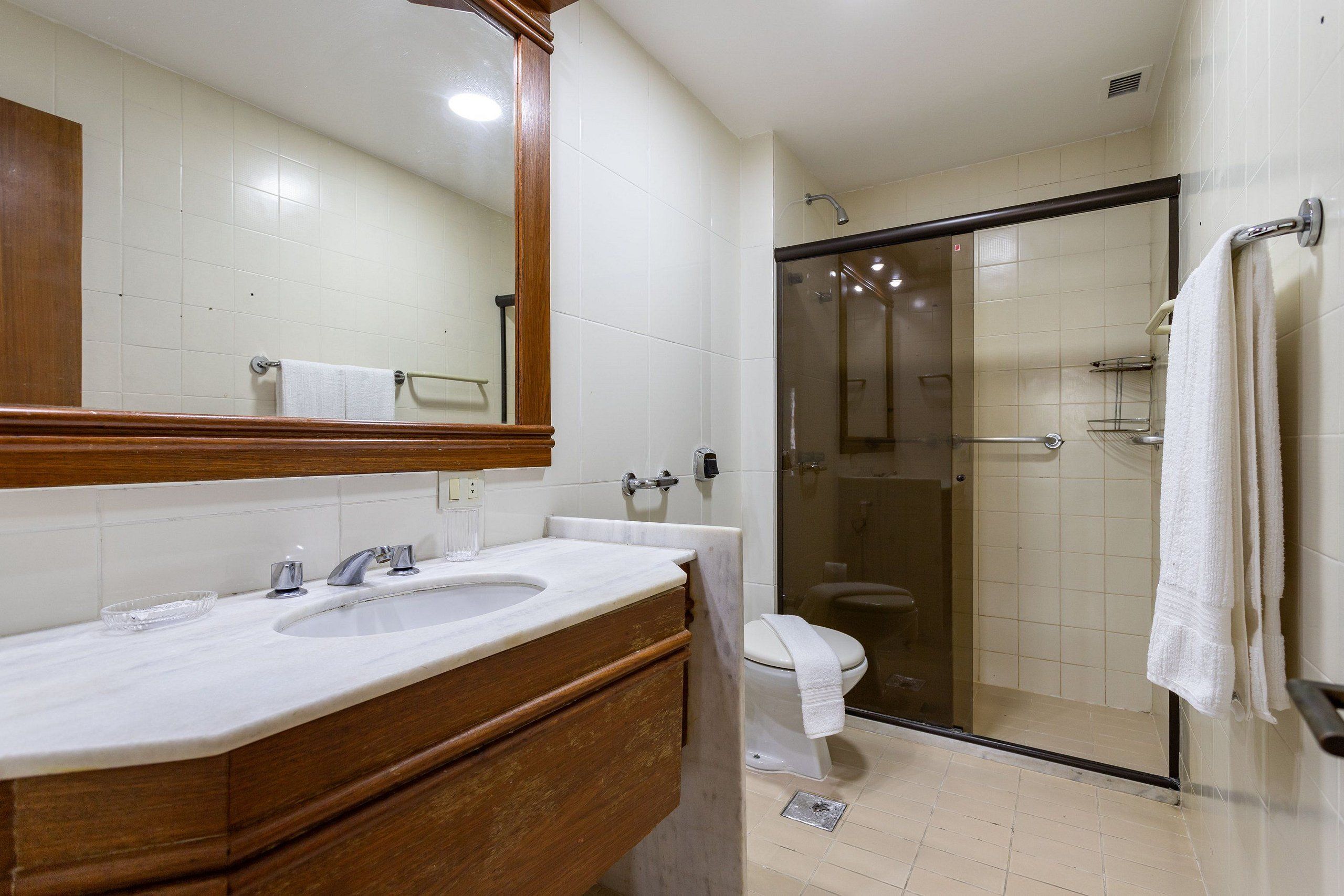 Une salle de bain avec un meuble-lavabo à deux vasques, des toilettes et une cabine de douche en verre.